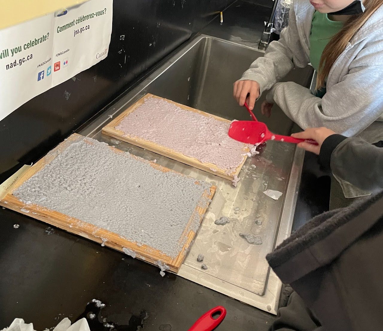 Students spread seed pulp on a board to dry. 