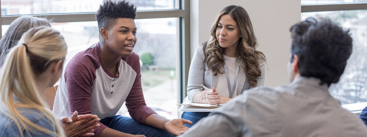 In a small group of adults and other youth, a teen boy shares his experience.