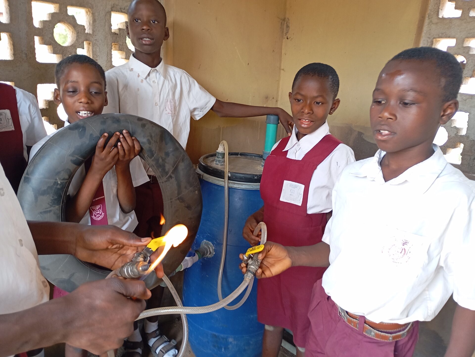 Four students hold tubes connected to a large vat. 