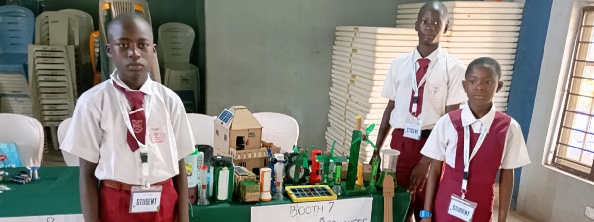 Students stand in front of a table showcasing their creations.