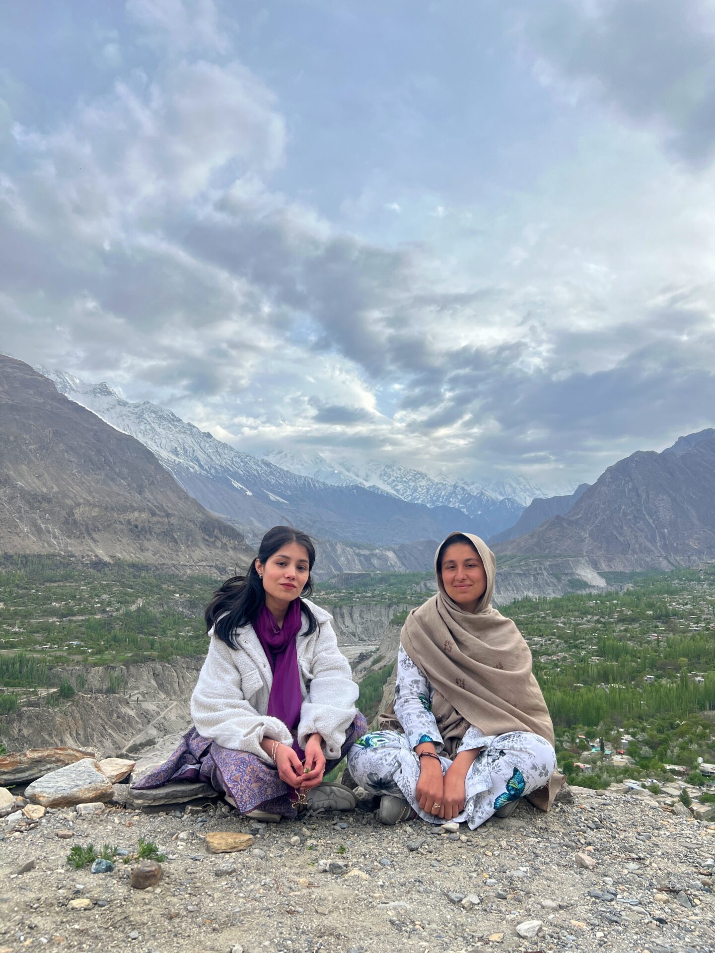 Two students sit among a mountain range