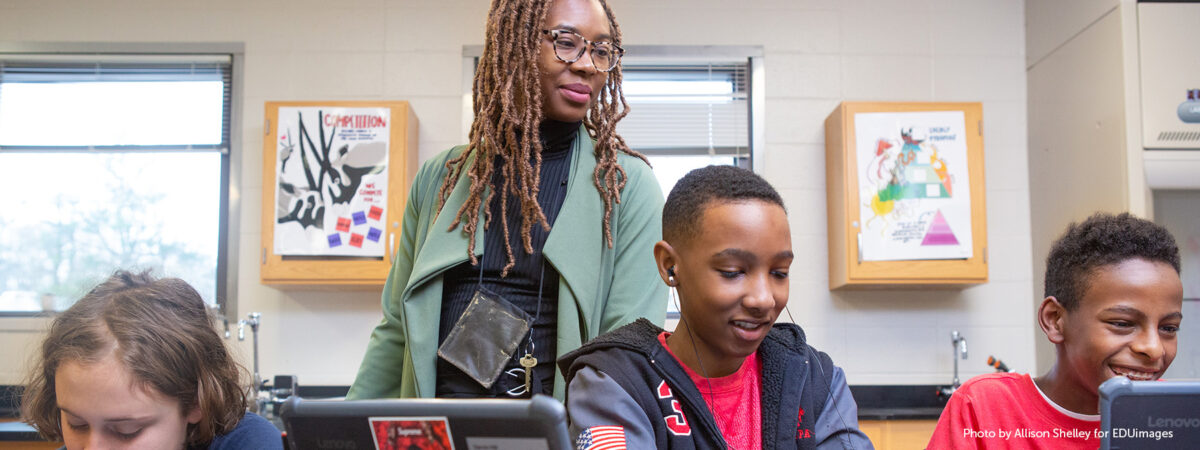 A teacher helps students during a coding lesson at Sutton Middle School.