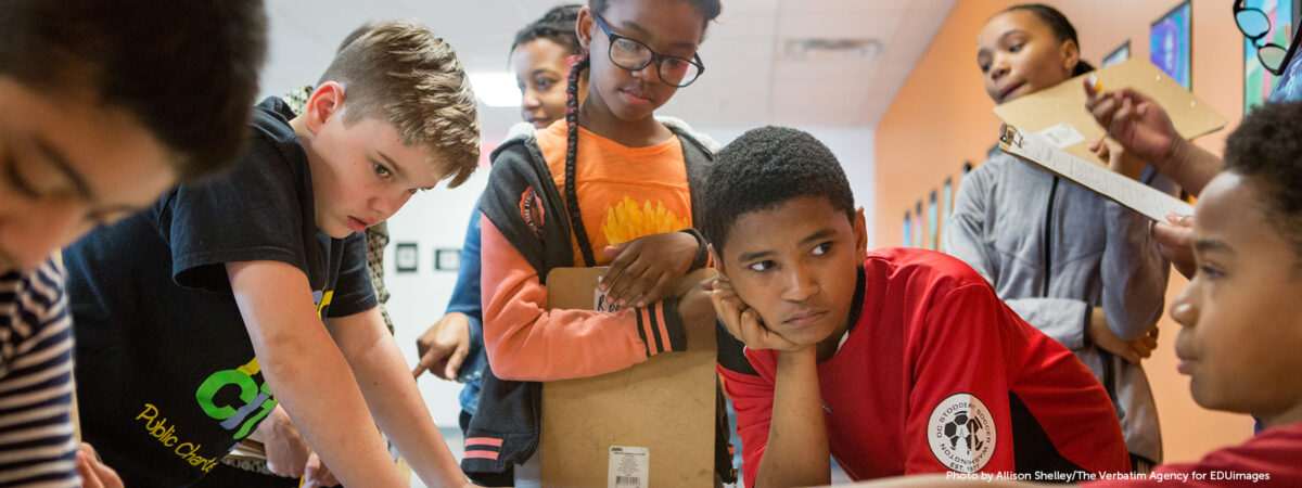 A middle school student explains the inspiration for his art project to classmates.