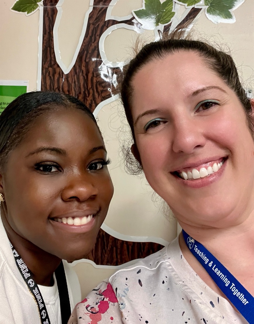 An image of two educators taking a selfie and smiling at the camera.