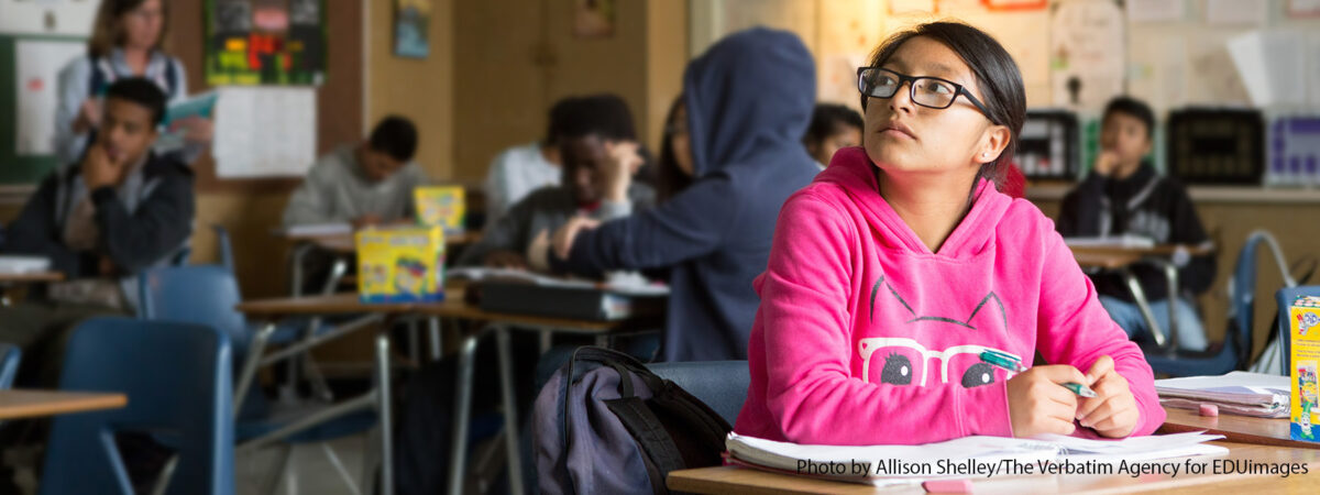 Student sitting in a classroom setting looking onward.