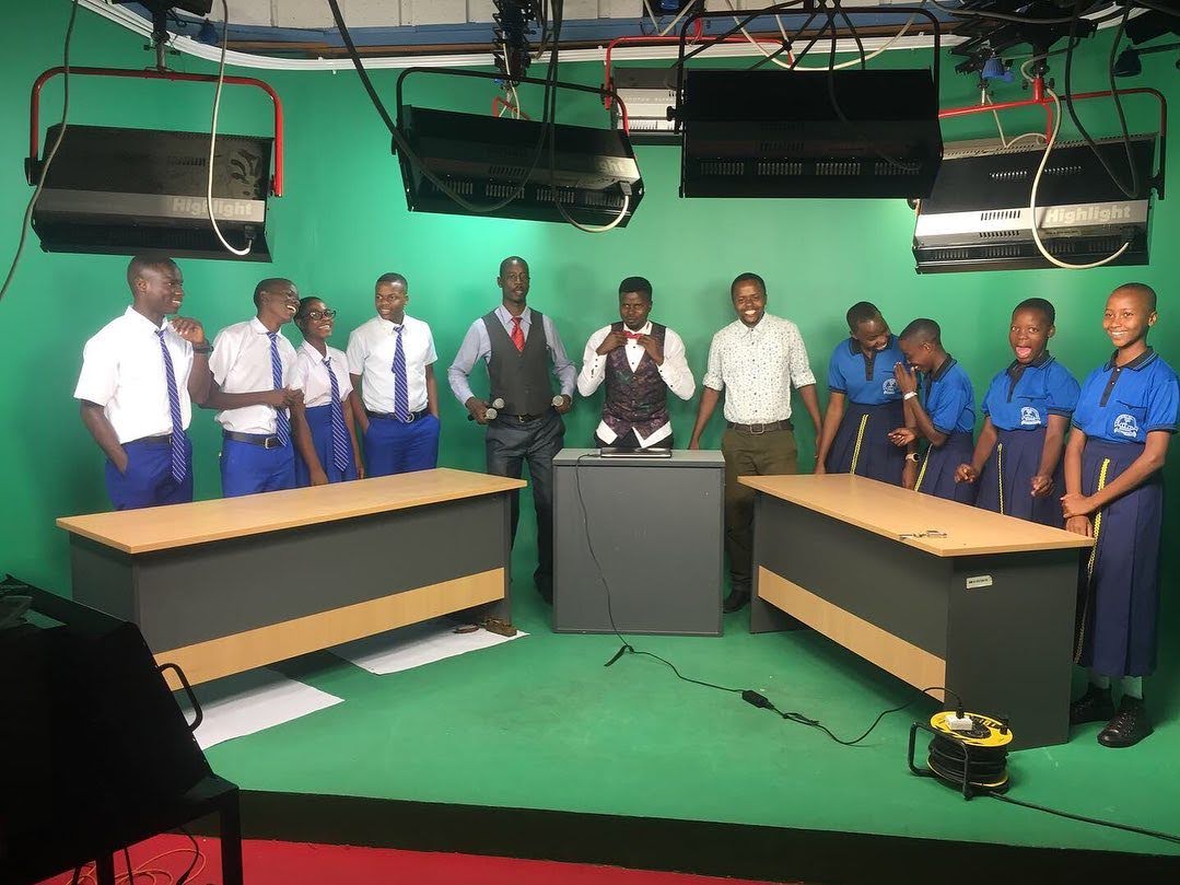 Students and teachers standing in front of a green screen in a production studio.