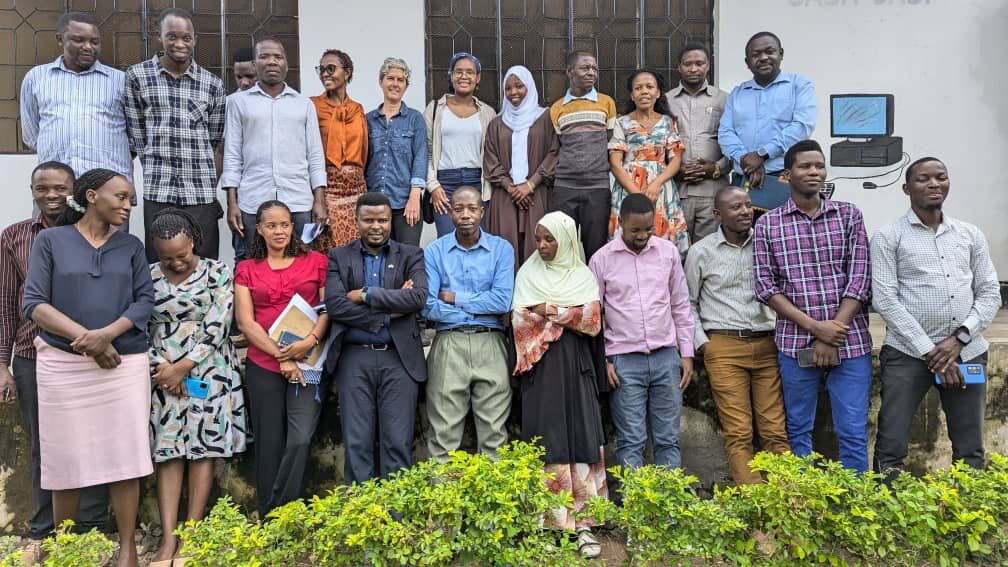 Group of people posing for a group photograph in front of a wall.