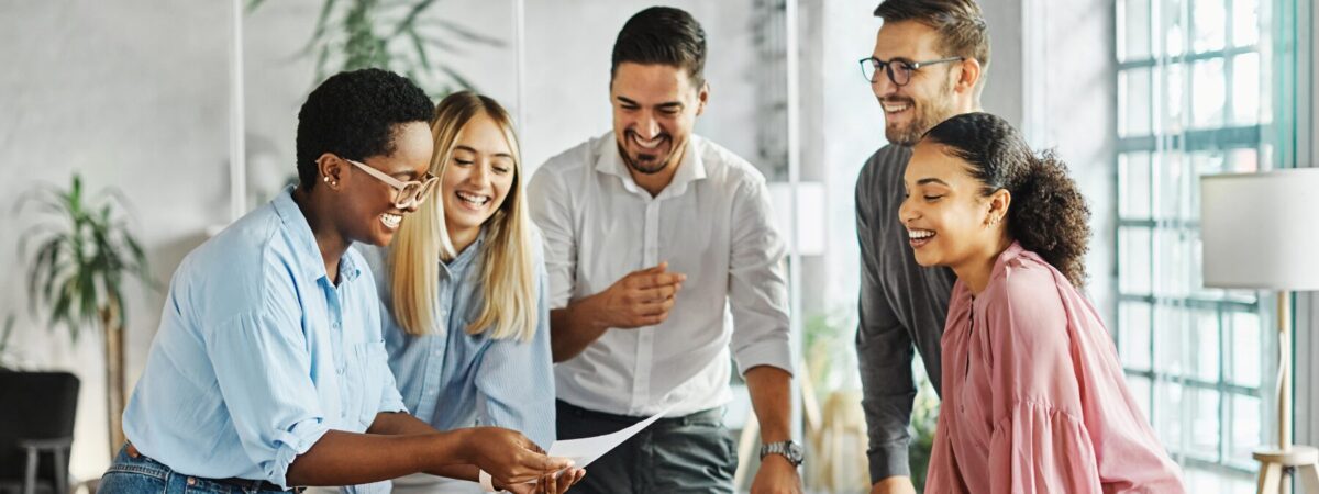 A stock image of a group of adults collaborating and looking over a piece of paper together.