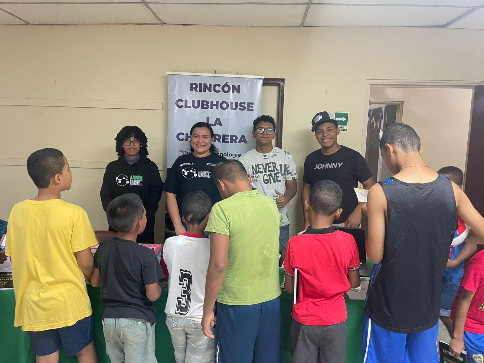 A group of students and a teacher standing in front of a Rincón Clubhouse banner.