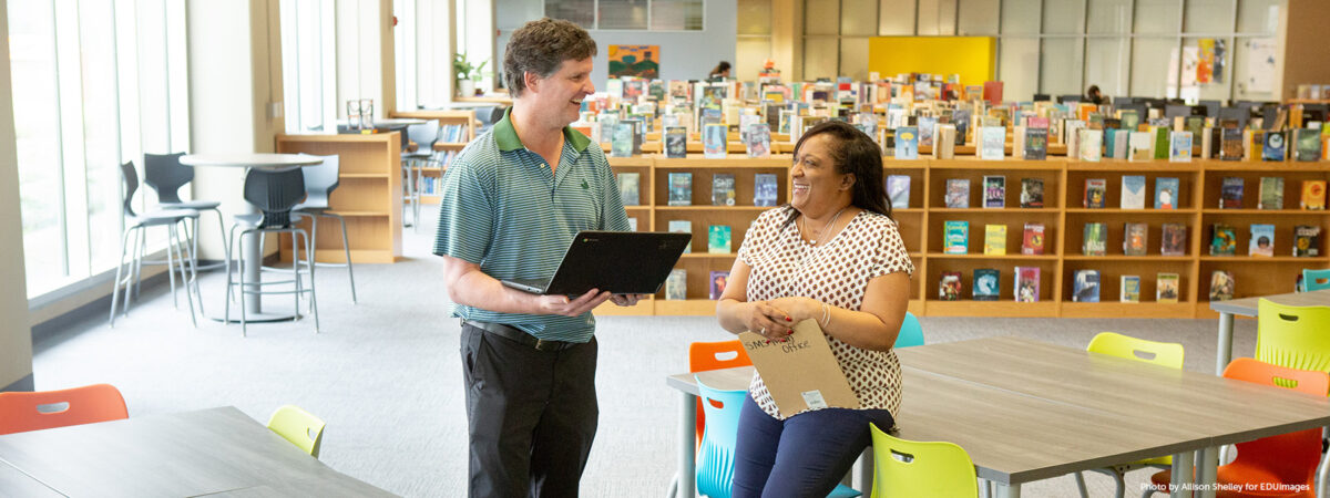 Two middle school teachers take a break in their school’s library.