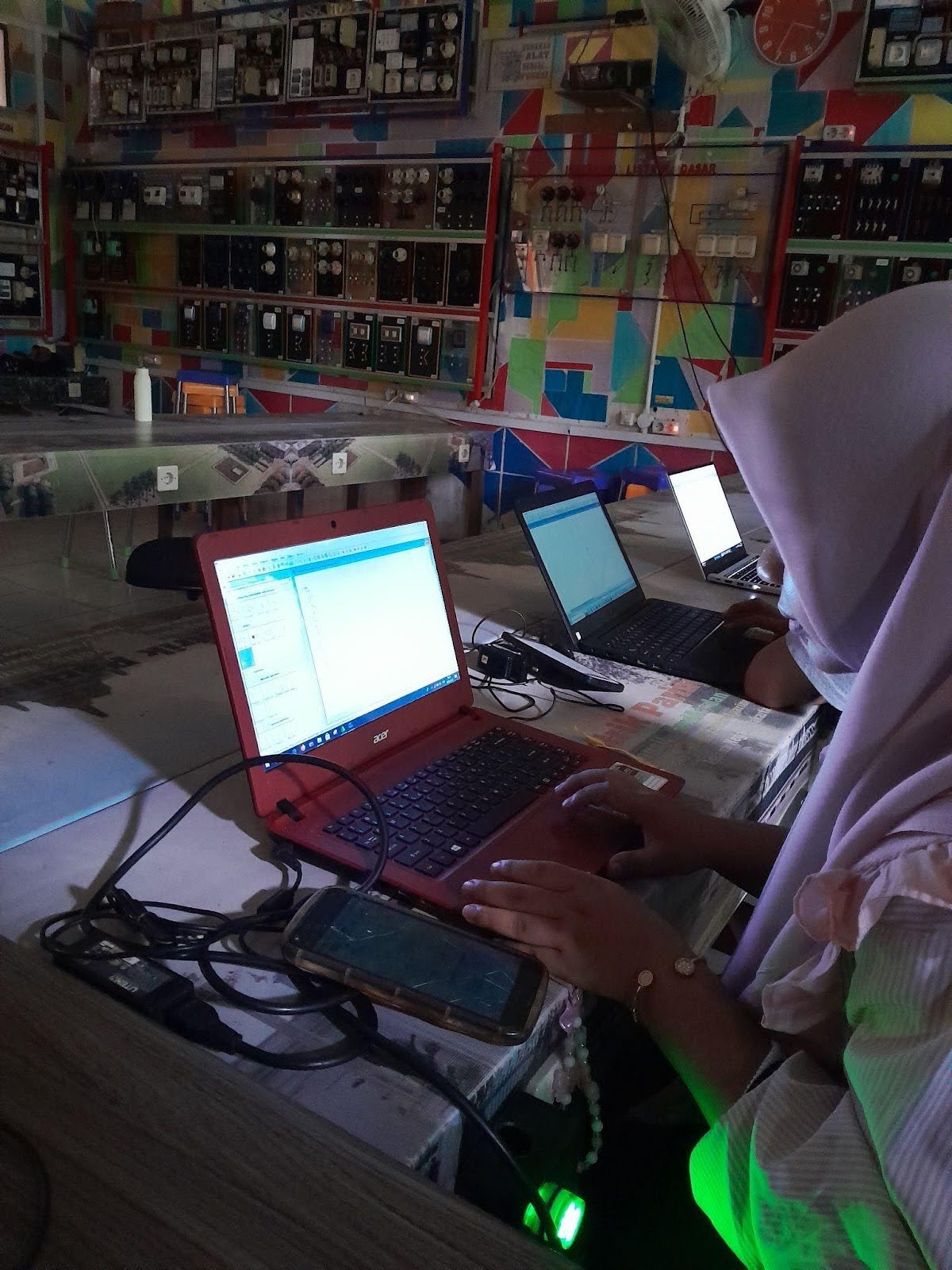 A student works on a laptop in a dimly-lit room. 