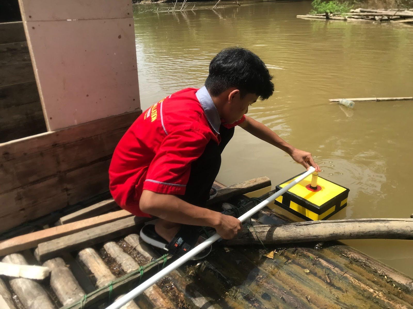 A student places a device into a body of water.
