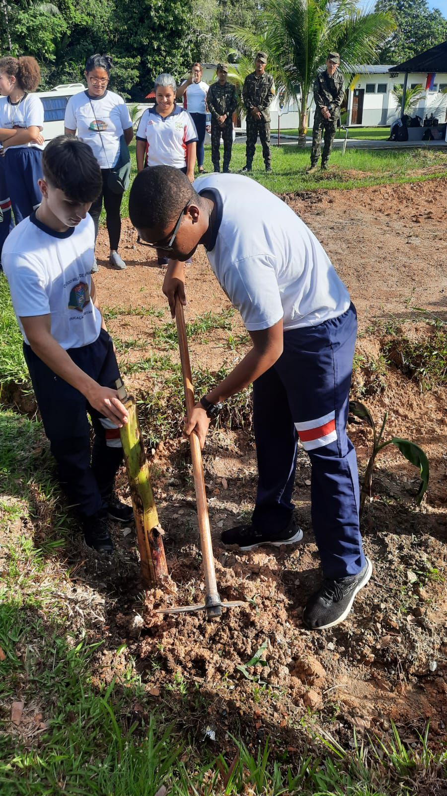 Two students shovel a hole in the ground