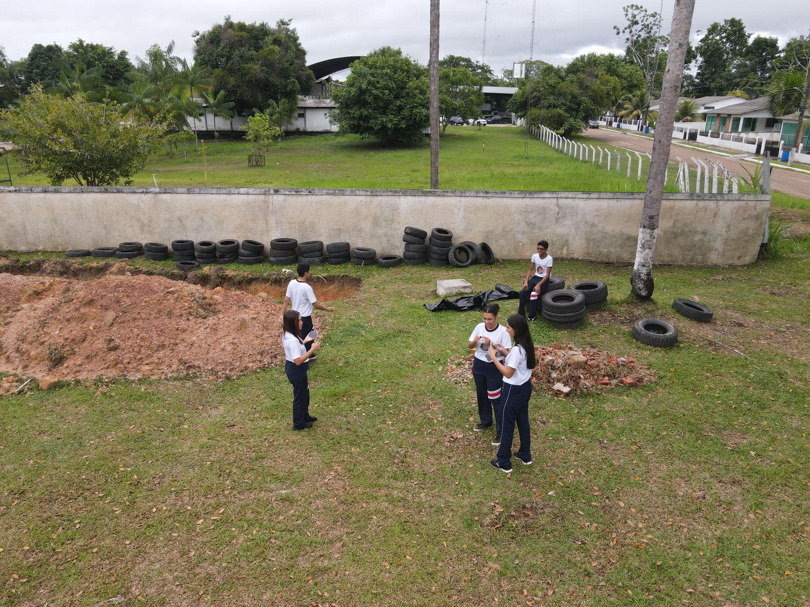 An aerial view of students outside standing near mounds of dirt