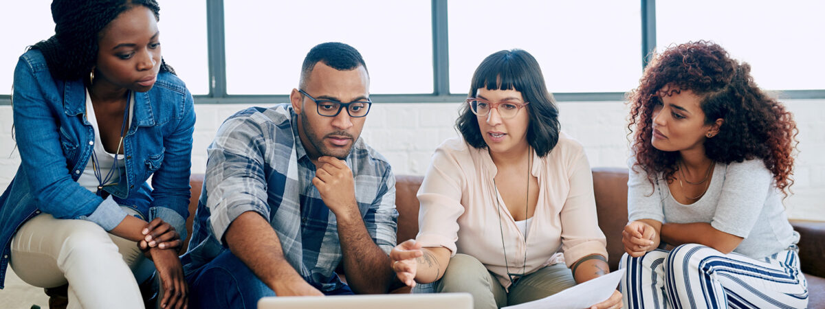 Shot of a group of colleagues using a laptop together in a modern office
