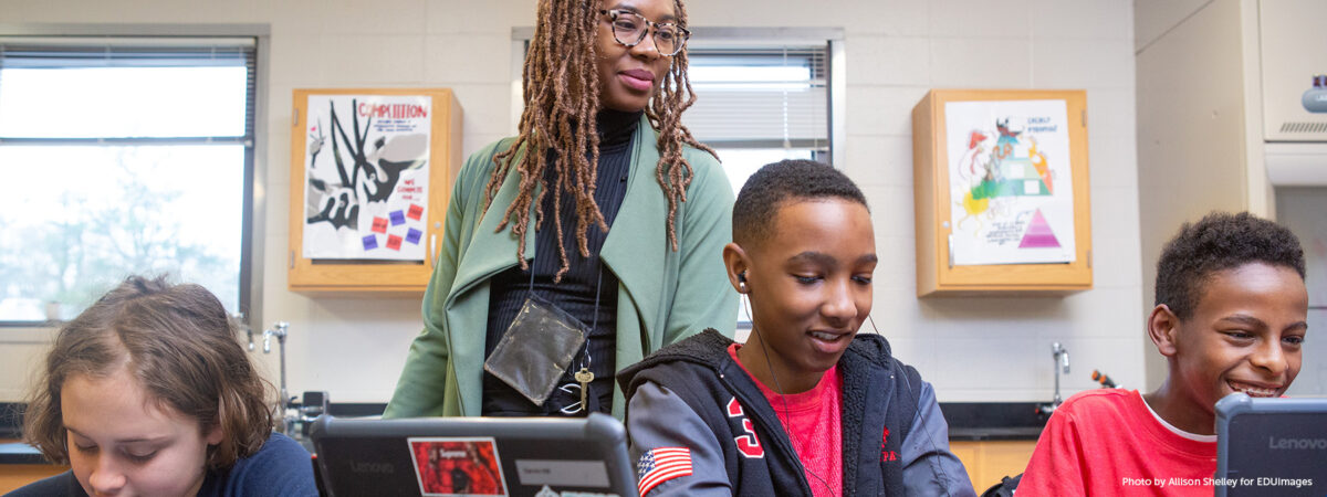 A teacher helps students during a coding lesson at Sutton Middle School.