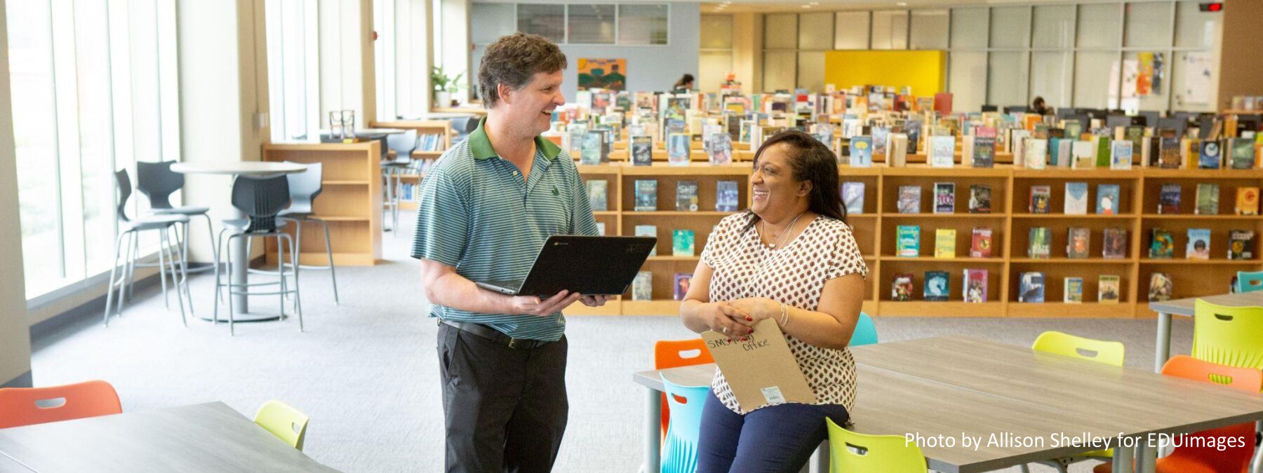 An image of two middle school teachers taking a break in their school’s library.
