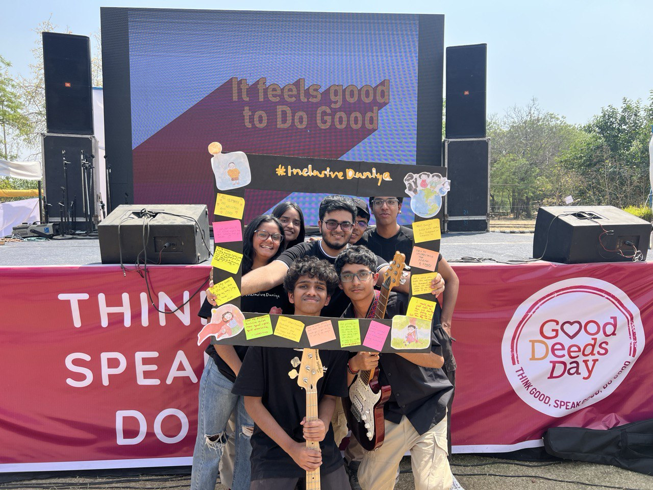 Six young people pose with guitars inside a handmade #InclusiveDuniya frame at a Good Deeds Day event stage.