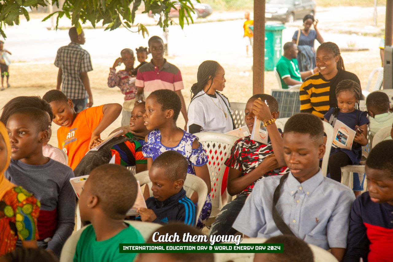 A group of young people are seated in a row of chairs