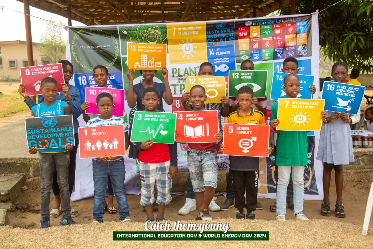 A group of young people hold up signs showing the icons of the UN Sustainable Development Goals