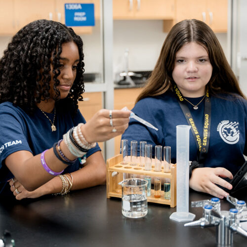 Two middle schoolers drop liquid into a vial in a science lab