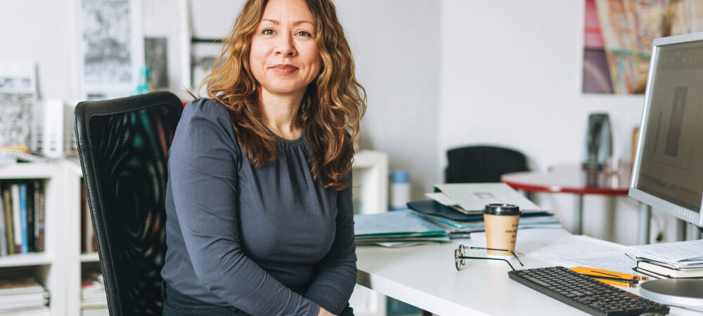 Portrait of charming smiling adult woman middle aged with curly hair architect designer manager working in bright modern office
