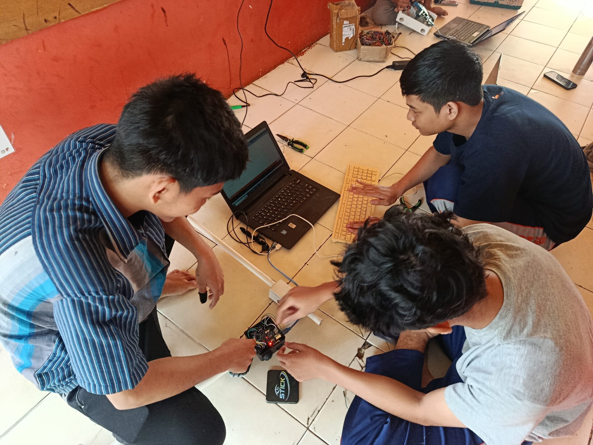 Students work together with devices while sitting on the floor