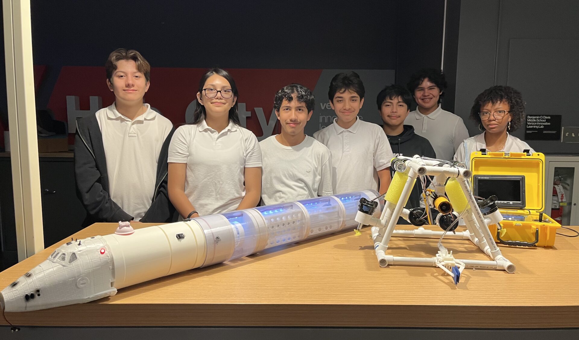 A group of students pose with their prototypes of spaceship and other devices.