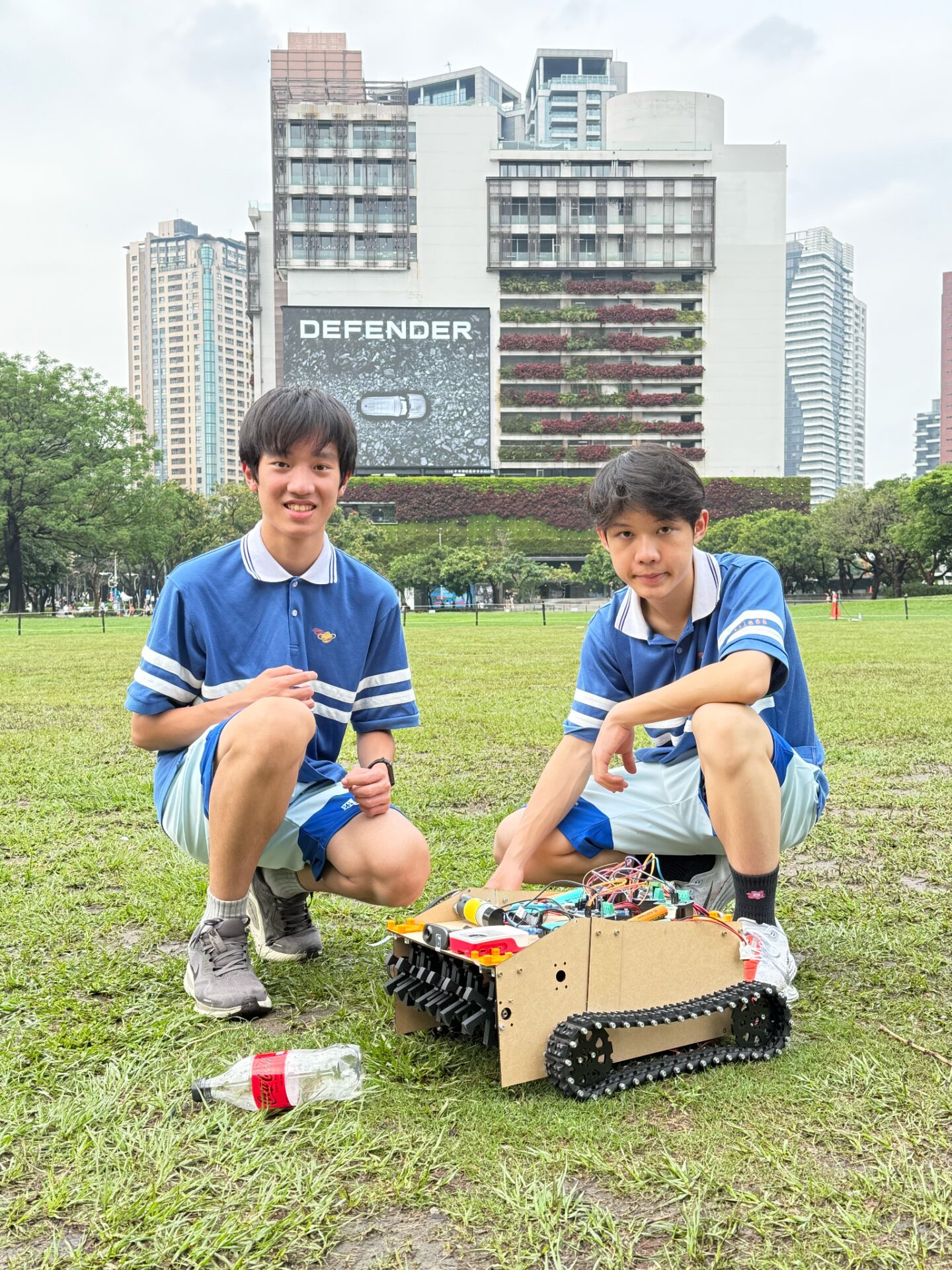 Two students pose crouched next to their robot.