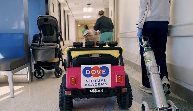 The back of the toy car with the girl driving it through the hospital hallway.