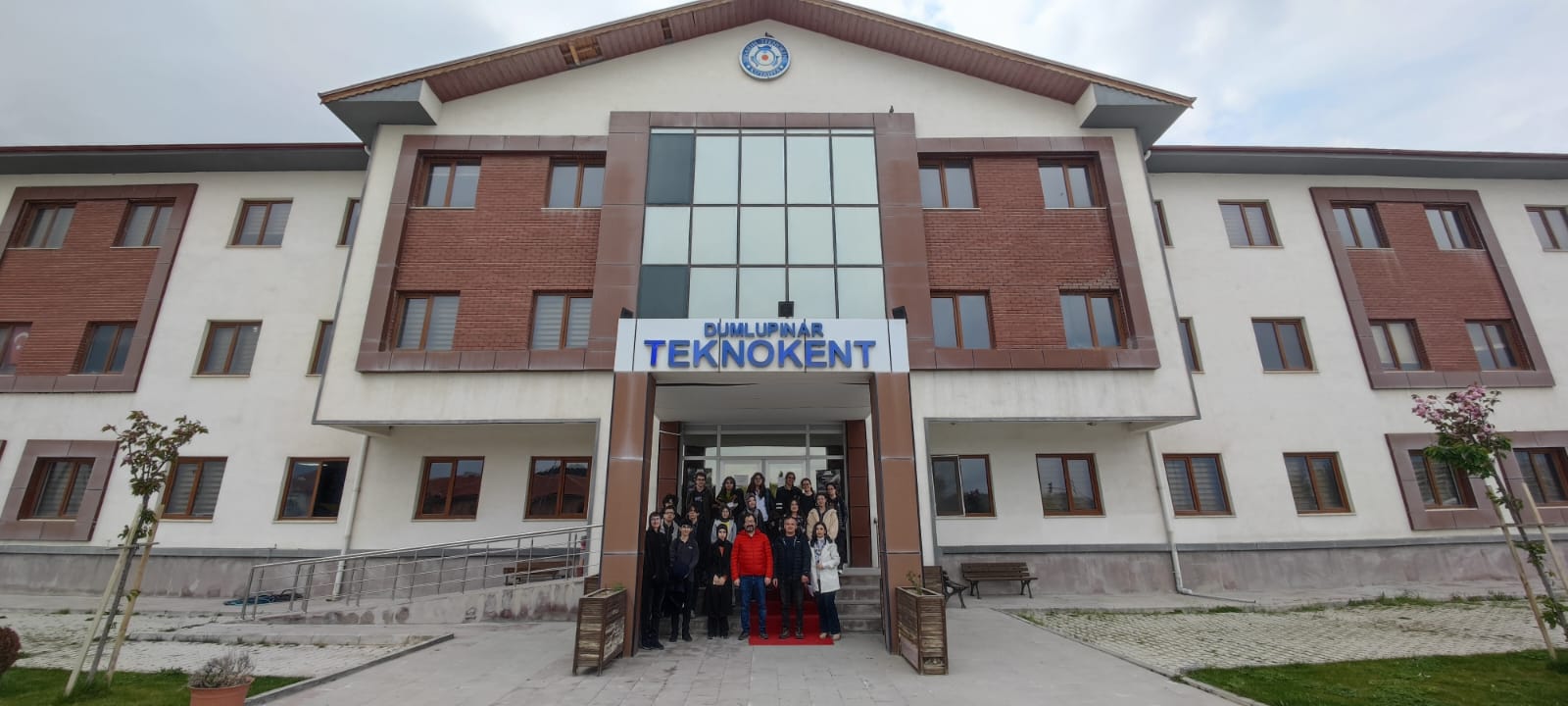 A wide shot of an office building with students gathered for a picture at the entrance.