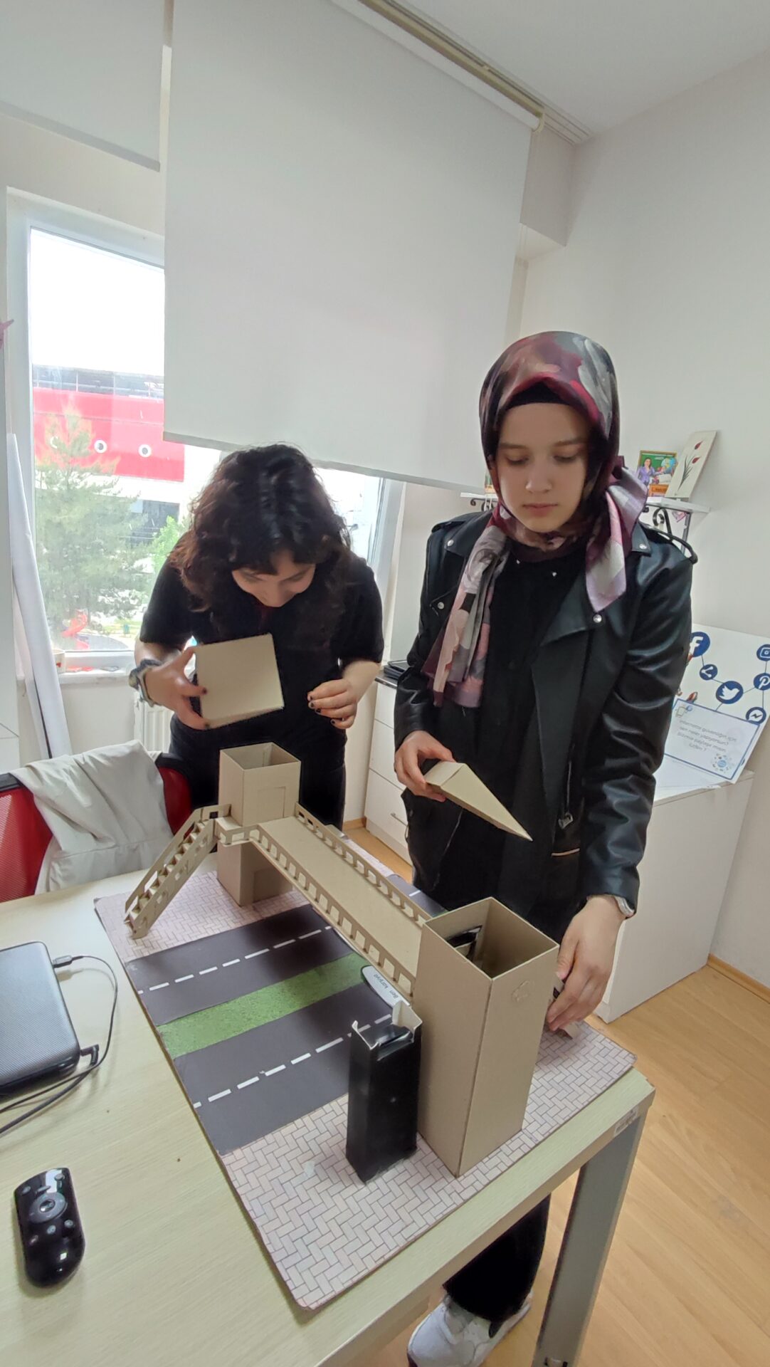 Two students construct a model out of cardboard.