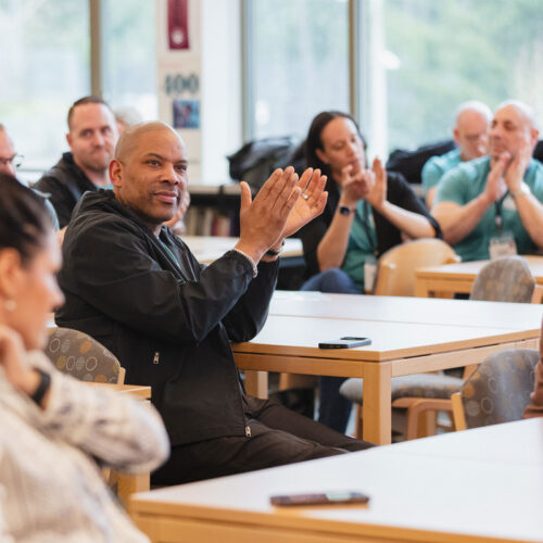 A group of adults clap in a school library