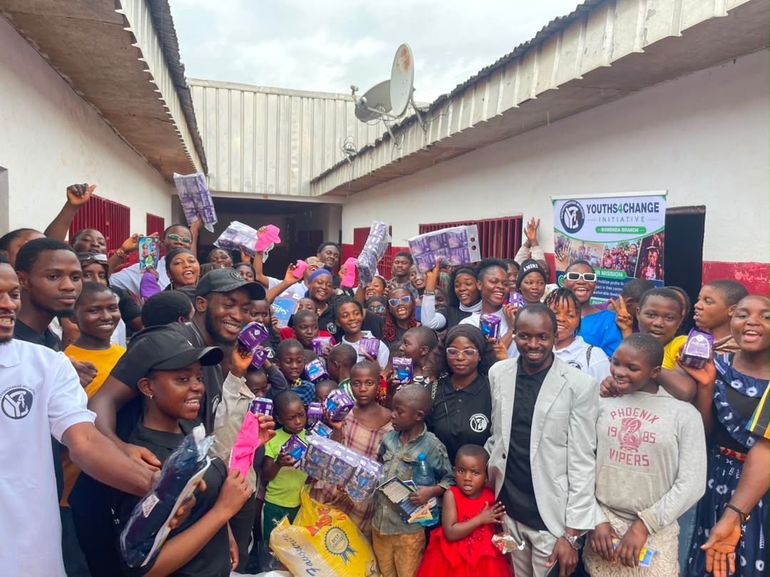 A large group of people pose for a photo while holding up menstrual pads.
