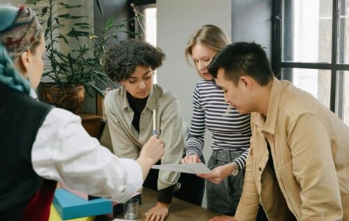 Four people collaborating around a table, reviewing materials together.