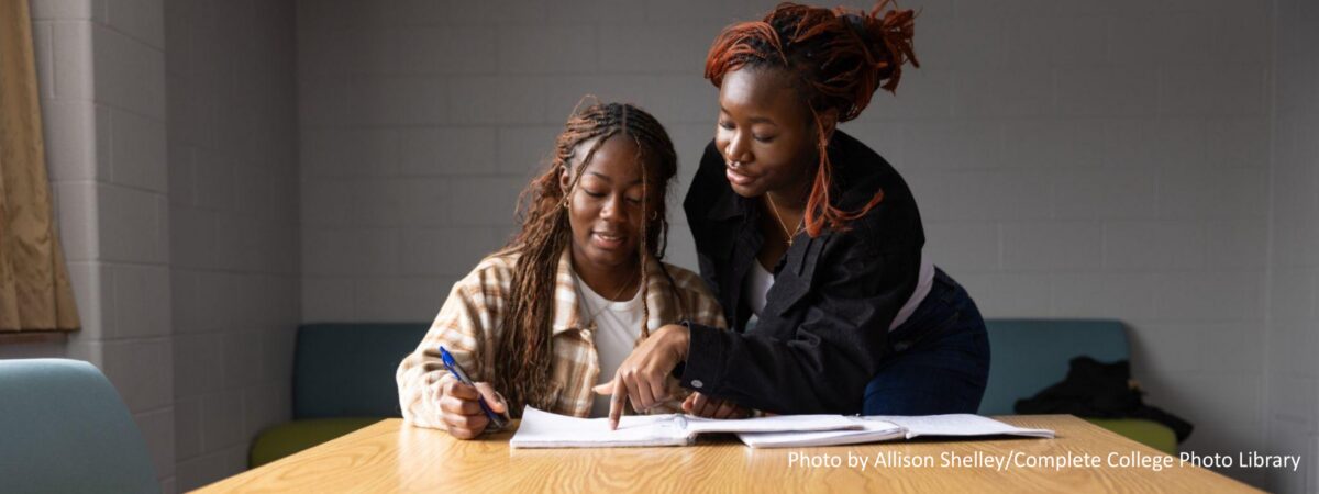 Black female students working together with a notebook in a residence hall common area on a college campus.