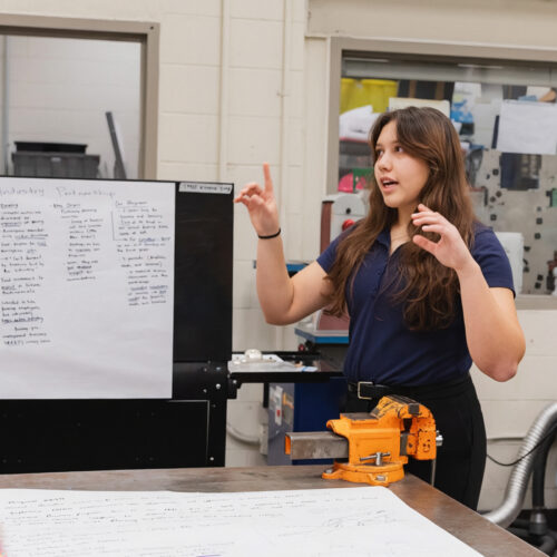 A student presents in front of a worktable